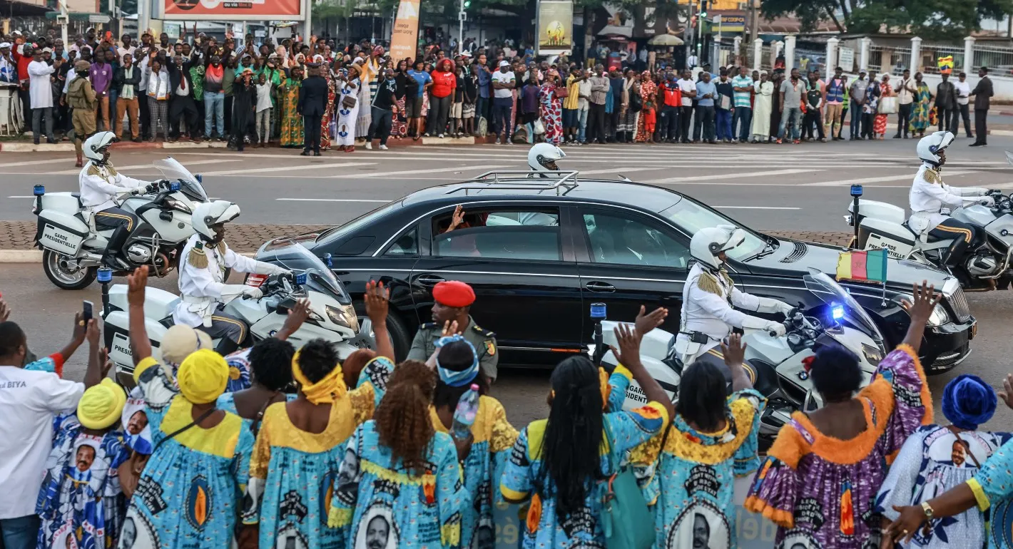 People wave as Paul Biya’s motorcade passes through Yaoundé on August 20, 2026. (AFP via Getty Images)